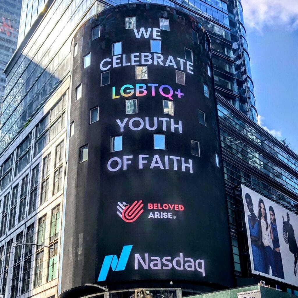 QYFD NASDAQ | GLAAD Exterior of NASDAQ building with text that reads "We celebrate LGBTQ+ youth of faith" with Beloved Arise and NASDAQ logos.