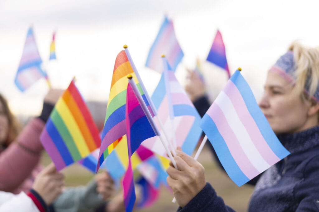 Hands waving and holding transgender pride flags, Lesbian and Gay pride flags, and bisexual pride flags