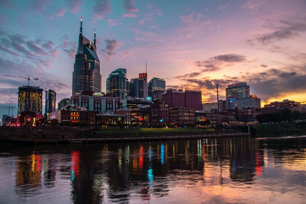 Downtown Nashville at Dawn or Dusk, the sun just sets or rises over the big city buildings, which reflect in the water before it