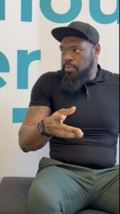 Screenshot 2024-04-04 at 115615 AM | GLAAD Chris Sutton (he/him), a black man wearing a back hat with a brown beard sits talking to GLAAD about LGBT Detroit, using his hands while he speaks.