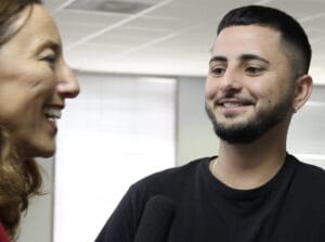 Screenshot 2024-04-17 at 31841 PM | GLAAD Daron Yates Perez, light brown complexion, with dark brown hair, and dark brown eyes, smiles wearing a black t-shirt at Monica Trasandes, side profile, fair complexion, smiling with brown, blonde hair tucked behind her ear inside a white room with tall windows covered by window shades.