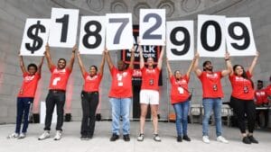 AIDS Walk New York Funds Raised Image | GLAAD GMHC Staff holding signs of total funds raised at NY AIDS Walk 2024
