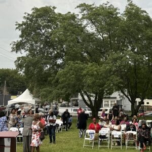 image_50758145 | GLAAD People gather at Leon Jordan Memorial Park in Kansas City, Missouri. The grass is green and chairs fill under a white tent.