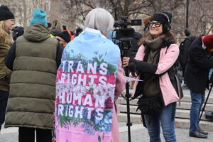 IMG_2533 | GLAAD Person wrapped in a "Trans Rights Are Human Rights" flag interviews with a reporter next to 14th street and Union Square subway station.