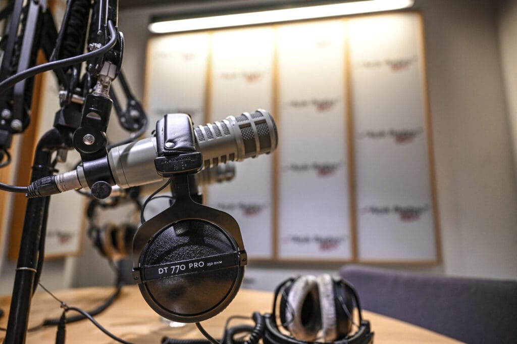 A photo shows a microphone and a headset in a studio