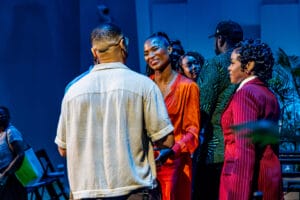 ABFF16-8 | GLAAD Group of friends chatting and smiling in a blue-lit room, wearing colorful outfits at a social event.