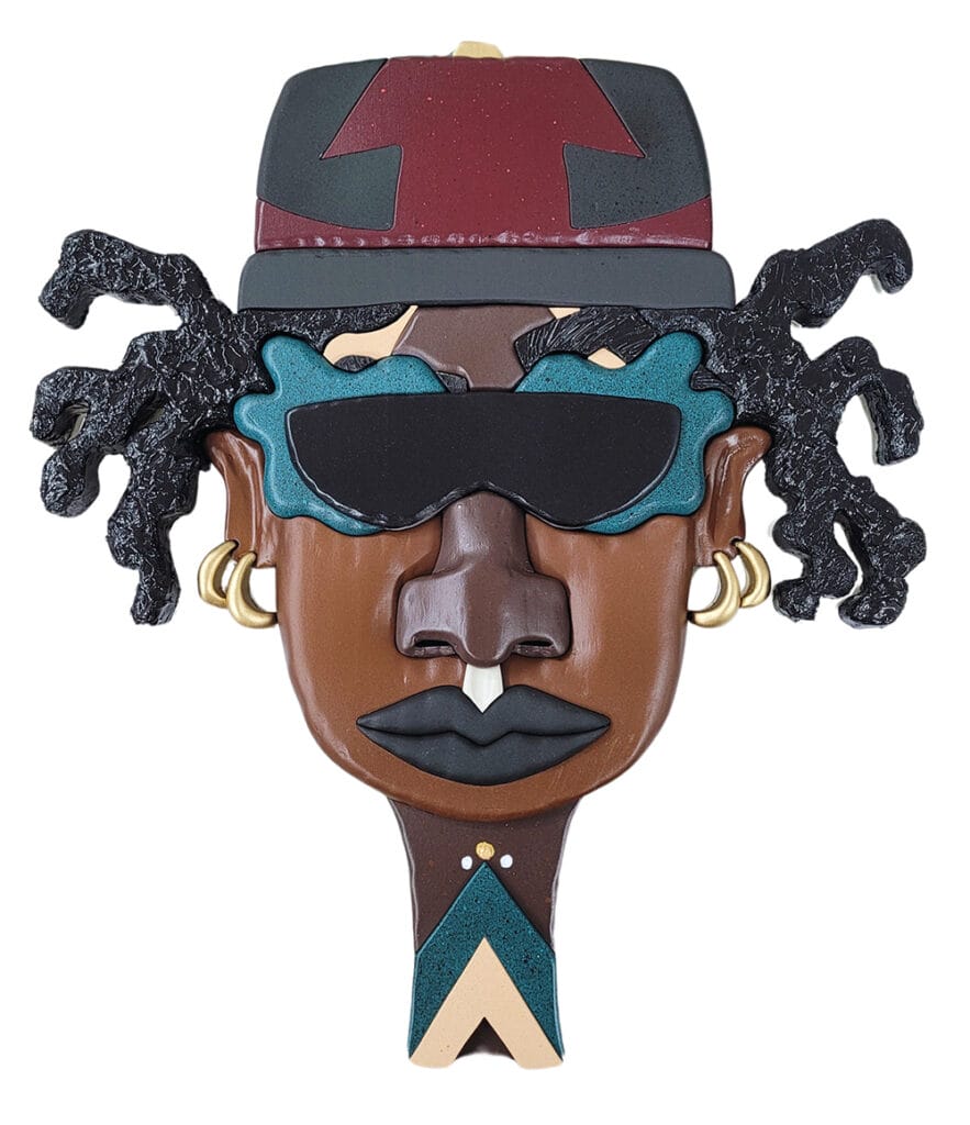 Stylized brown-faced sculpture with teal sunglasses, gold hoop earrings, black lips, and a red hat; geometric teal and beige necklace beneath the chin.