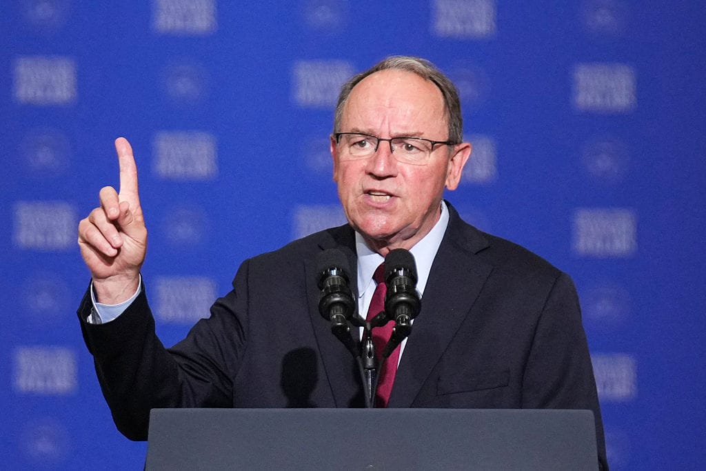 US Representative Tom Tiffany, Republican from Wisconsin, speaks before US Vice President JD Vance delivers remarks on the administration's work to combat fraud in Milwaukee, Wisconsin, on July 8, 2026. | GLAAD Man in a suit and red tie speaks at a podium with two microphones, raising his index finger as he makes a point.